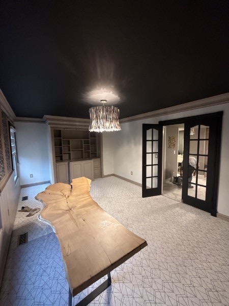 Finished dining room with a black painted ceiling, light walls, built-ins, and black French doors
