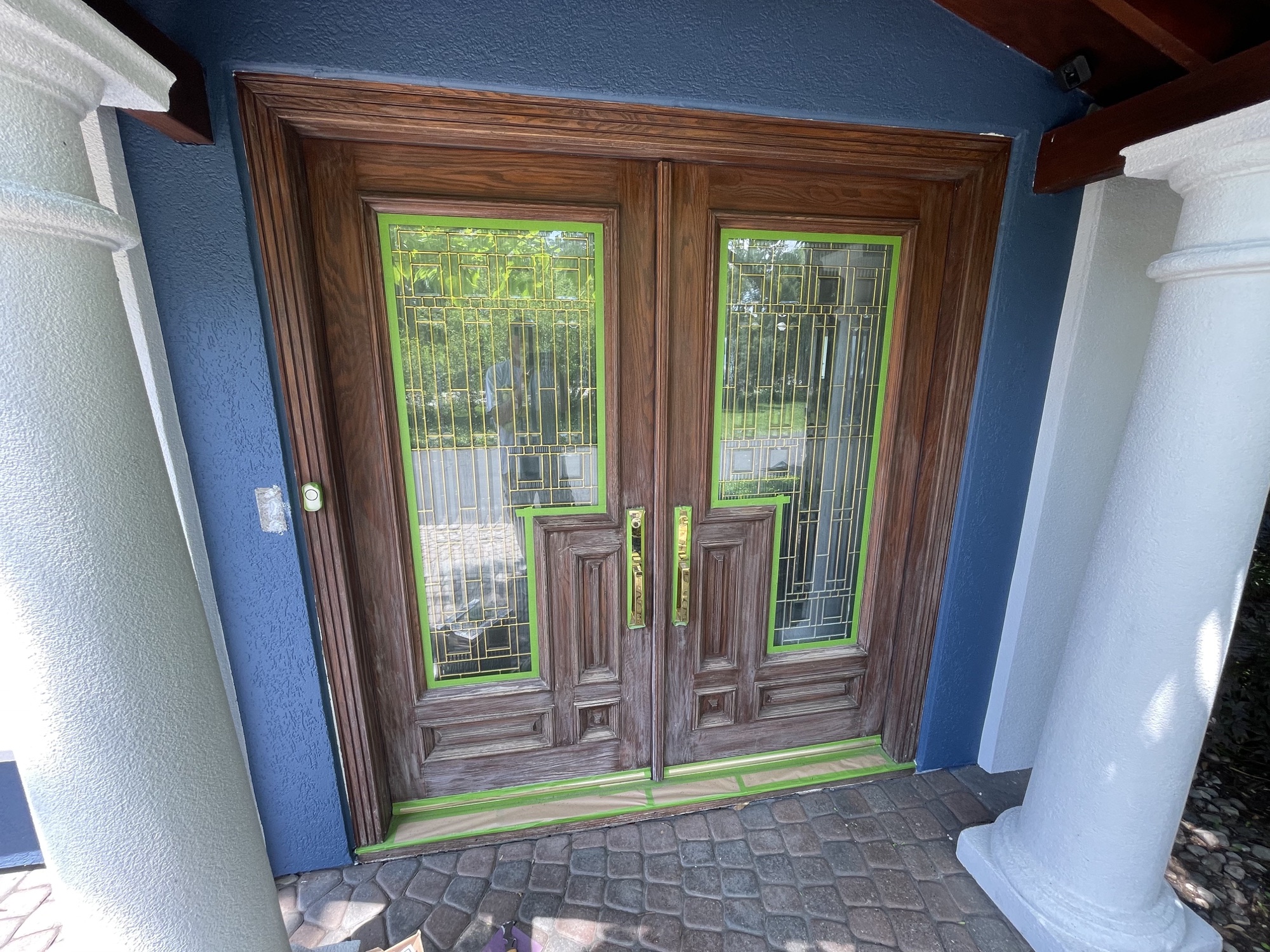 Weathered wood double entry doors masked before refinishing